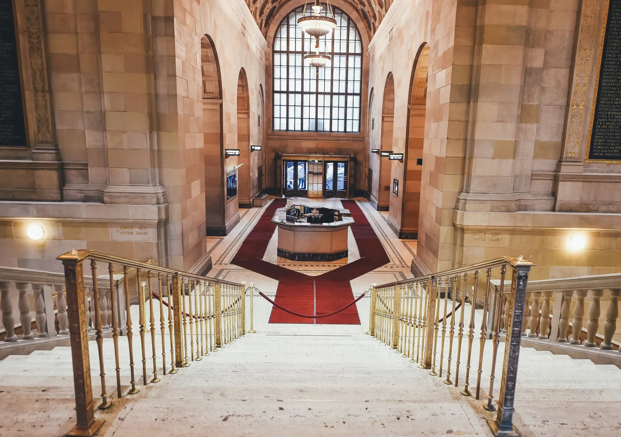 A marble entrance hall with a grand staircase and brass railings