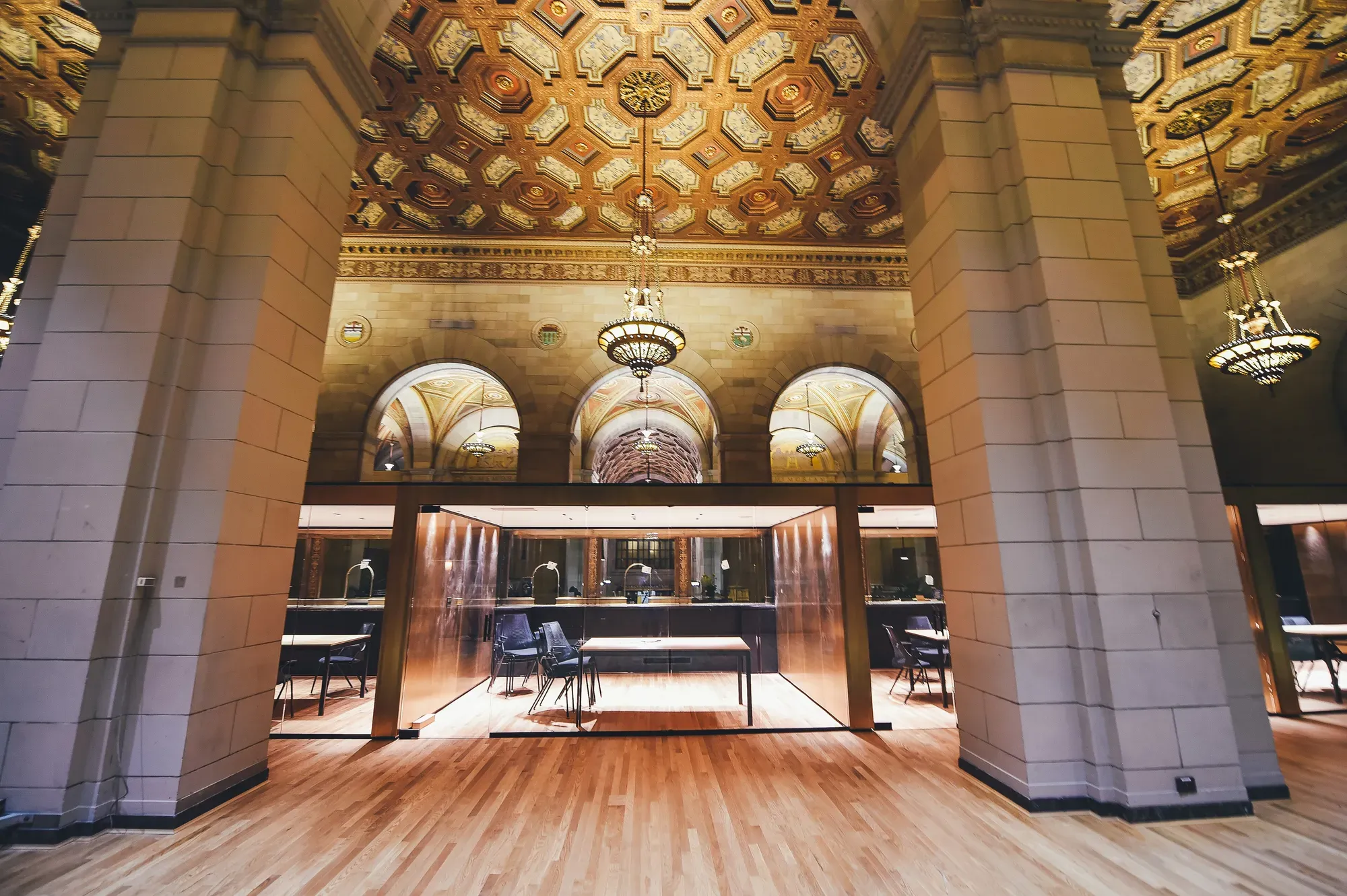 A workspace under a gilded coffered ceiling, stone columns and warm light